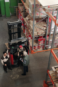 A forklift driving by shelves in a warehouse