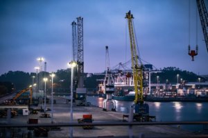 Twilight View of a Vacant Area at a Loading Dock Showing Two Trucks, Cranes, and Other Heavy Load Handling Systems