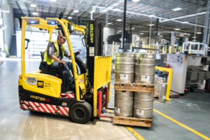 Worker moving heavy barrels in a facility