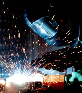 An industrial worker welding a metal bar