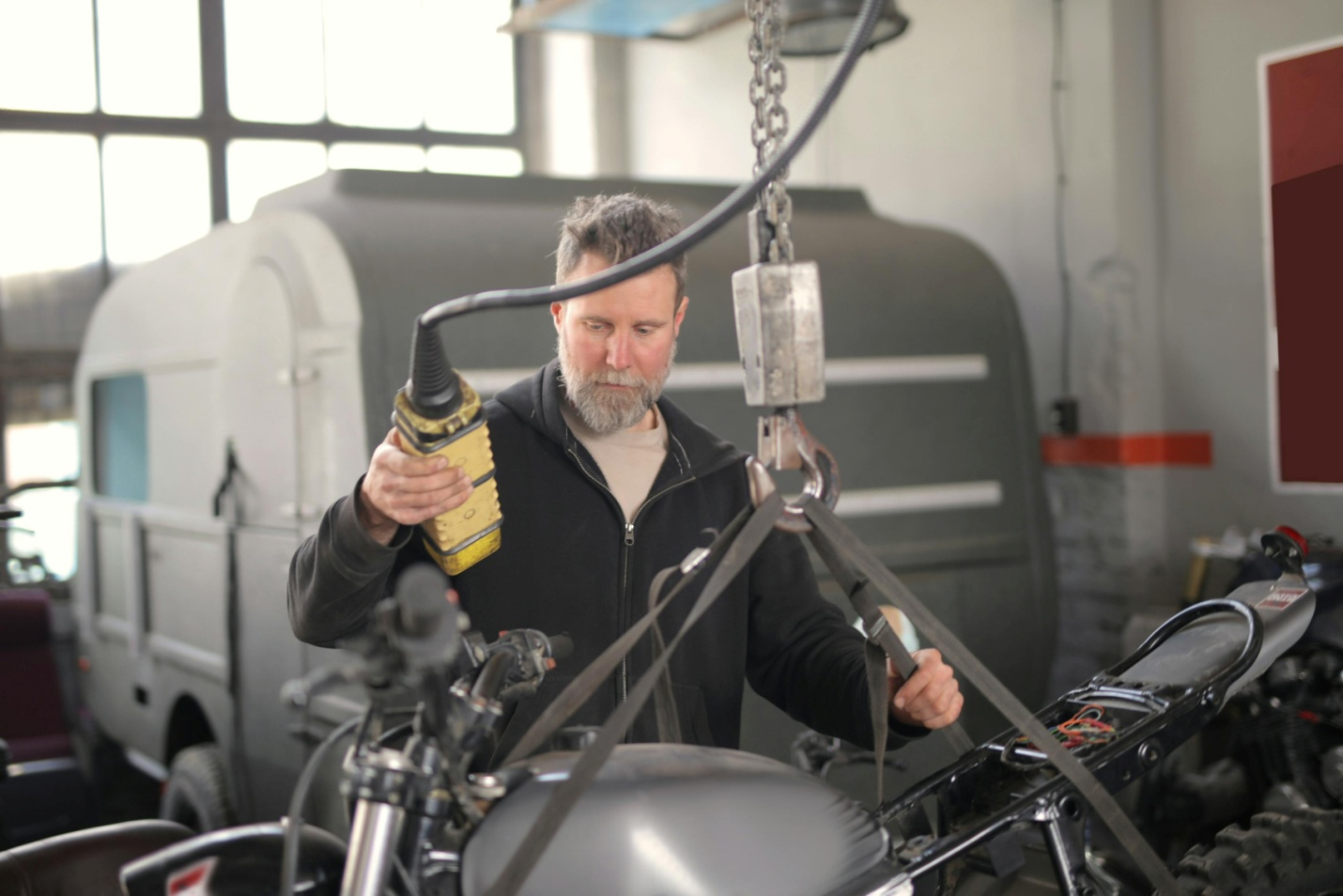 A man tying a motorbike to lifting-equipment