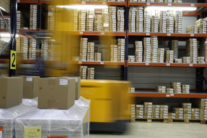 A forklift driving by shelves in a warehouse