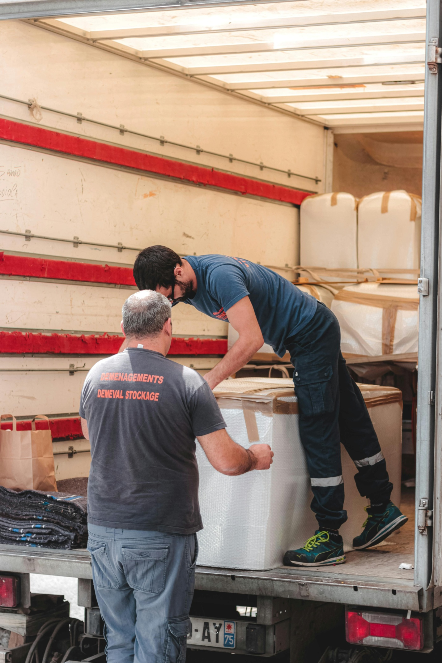 Two people taking out a huge box out of a truck